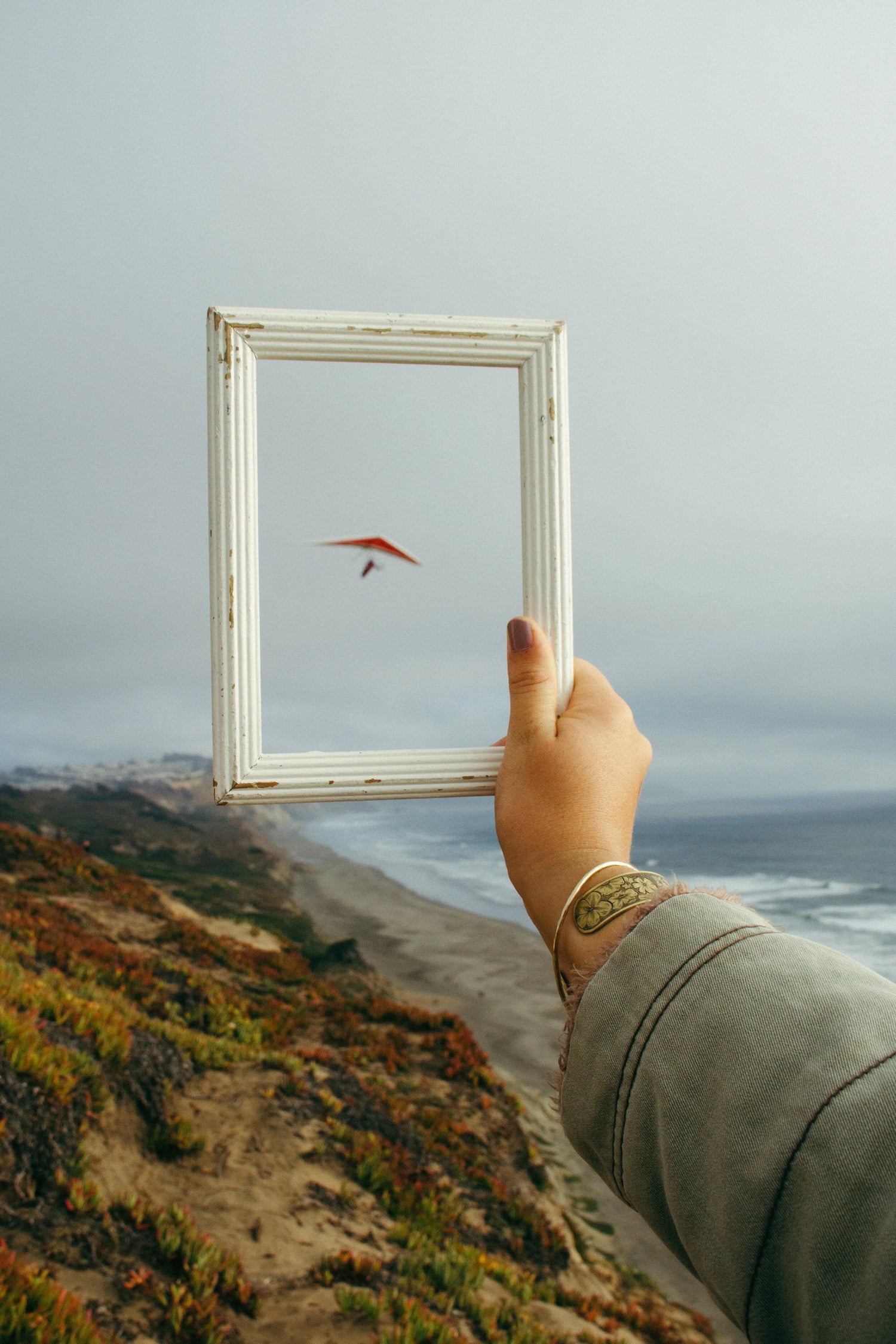 A woman holds a frame over a nature landscape